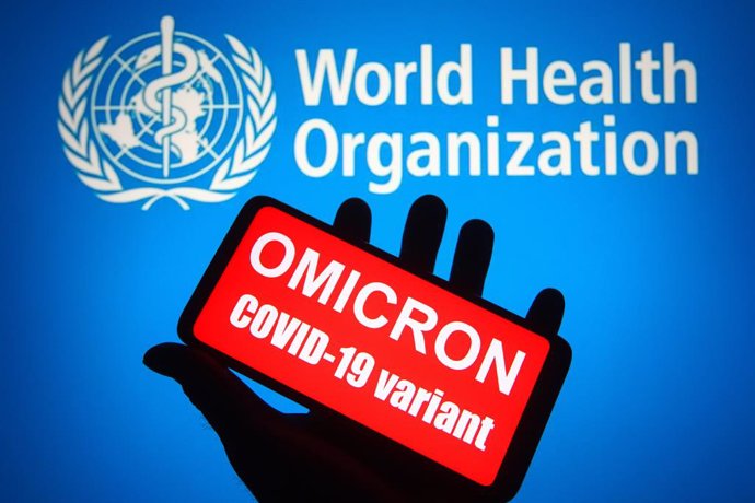 26 November 2021, Ukraine, ---: An illustration photo shows words that say "Omicron COVID-19 variant" displayed on a mobile phone screen in front of the World Health Organization (WHO) logo in the background. The mutated strain, called "Omicron" and des