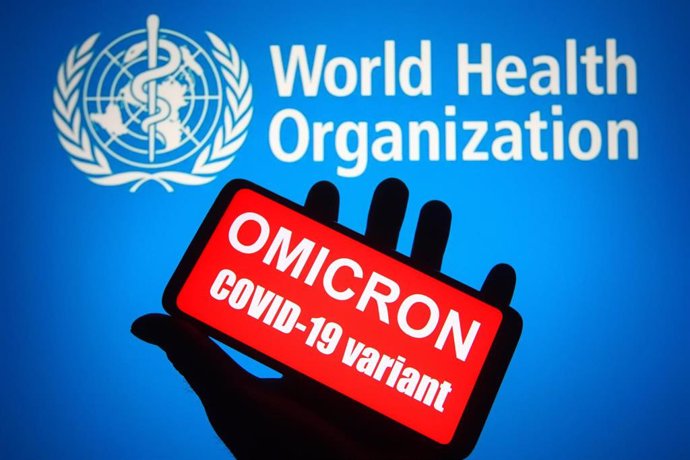 26 November 2021, Ukraine, ---: An illustration photo shows words that say "Omicron COVID-19 variant" displayed on a mobile phone screen in front of the World Health Organization (WHO) logo in the background. The mutated strain, called "Omicron" and des