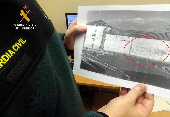 Agente con una fotografía del grafiti de la ermita de Maoño