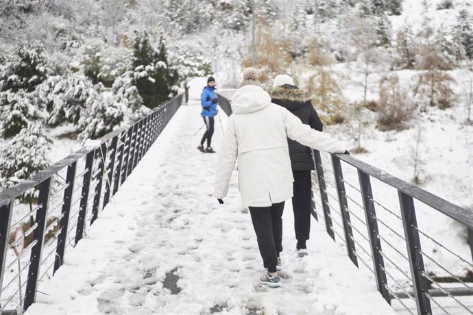 Tres personas caminan sobre un puente nevado, a 28 de noviembre de 2021, en Pamplona, Navarra (España). Un total de 31 provincias se encuentran bajo diferentes niveles de riesgo por nieve, lluvia, viento, fuerte oleaje, deshielo y temperaturas mínimas, 