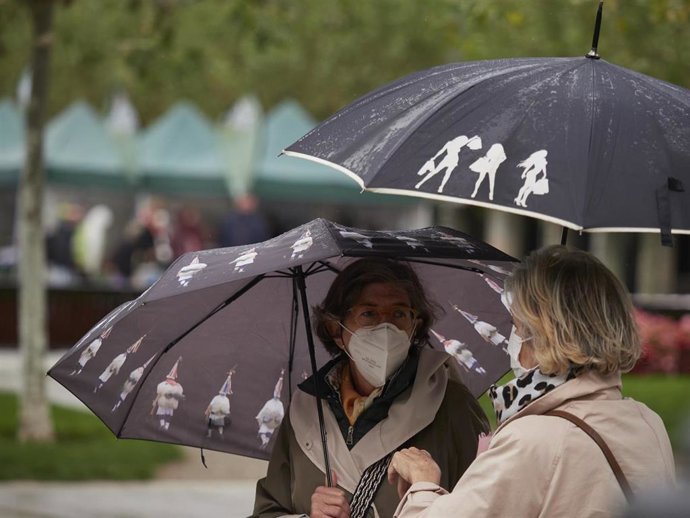 Archivo - Transeúntes pasean por una calle protegidos con mascarilla. 