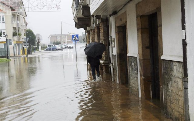 Un hombre camina por una vía inundada debido a las fuertes lluvias registradas en Ampuero, Cantabria, (España). 
