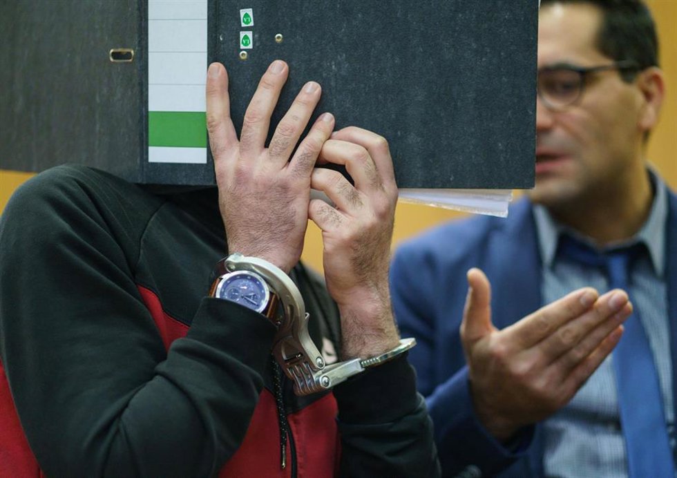El condenado Taha Al-Jr se cubre la cara con una carpeta. 