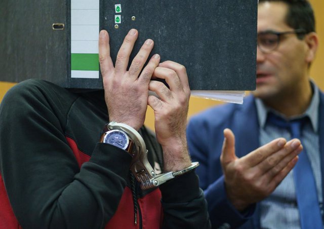30 November 2021, Hessen, Frankfurt_Main: Iraqi defendant Taha Al-J. (L) coveres his face with a folder as he enters the courtroom of the Frankfurt's Higher Regional Court before a verdict is pronounced. The Federal Prosecution has accused Taha of genocid