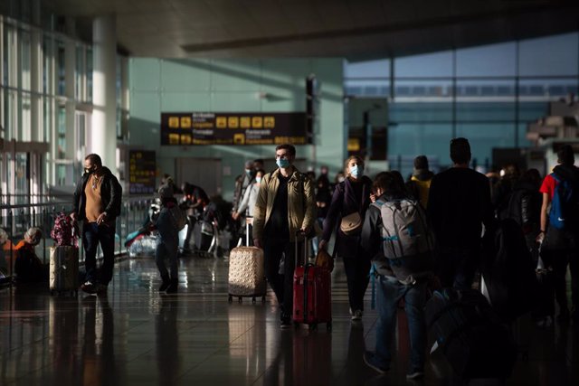 Varios pasajeros con maletas en el aeropuerto de El Prat, en Barcelona