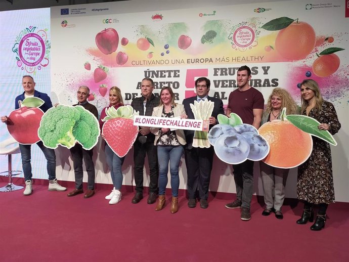 Los promotores de la campaña posando con imágenes de frutas y verduras.