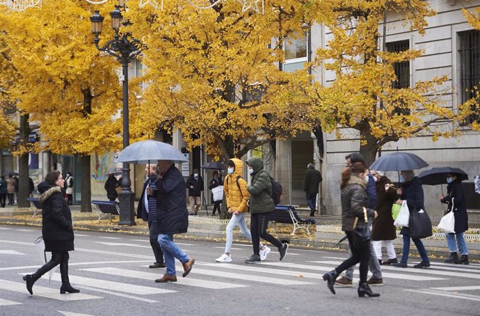 Archivo - Varias personas con paraguas cruzan un paso para peatones en Santander.- Archivo