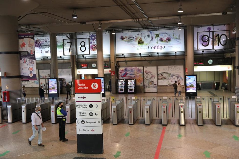 Archivo - Una vigilante de seguridad y un hombre caminan por el estíbulo de la estación de Madrid-Puerta de Atocha
