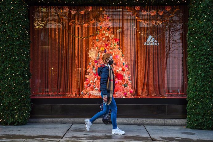 Archivo - 19 November 2020, England, London: A woman wears a face mask passes in front of a window that displays Christmas decorations at Oxford Street while England continues a four week national lockdown to curb the spread of coronavirus. Photo: Kirst