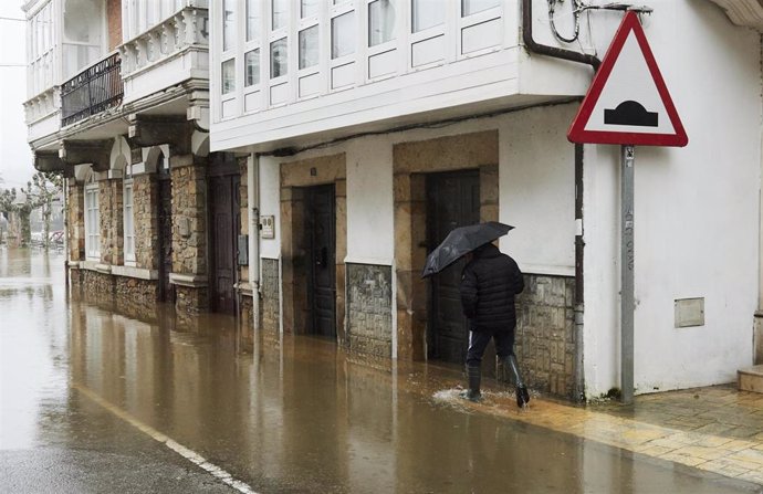 Un hombre camina por una vía inundada debido a las fuertes lluvias registradas