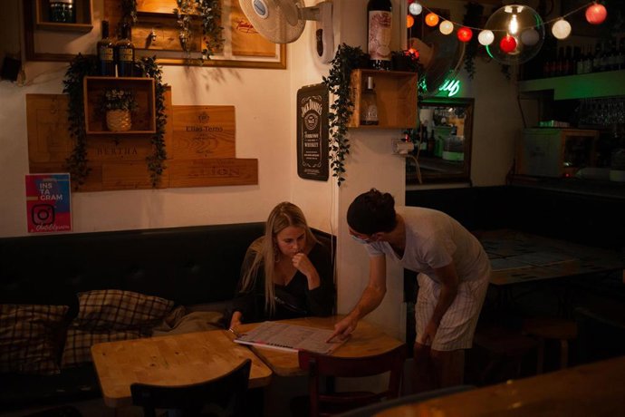 Archivo - Una camarera atiende a una mujer en un bar de una calle céntrica de Barcelona, a 14 de octubre de 2021, en Barcelona, Catalunya (España). A partir de este viernes en Cataluña se terminarán las limitaciones de aforo en los equipamientos cultura