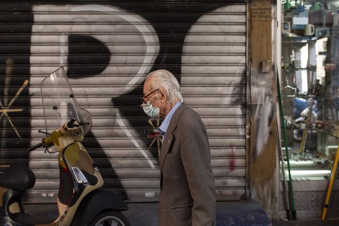 01 December 2021, Greece, Athens: An elderly man wearing a mask walks through a market of Athens. Greeks over the age of 60 must be vaccinated at least once by 16 January 2022, otherwise they will have to face a monthly fine of 100 euros. Photo: Socrate