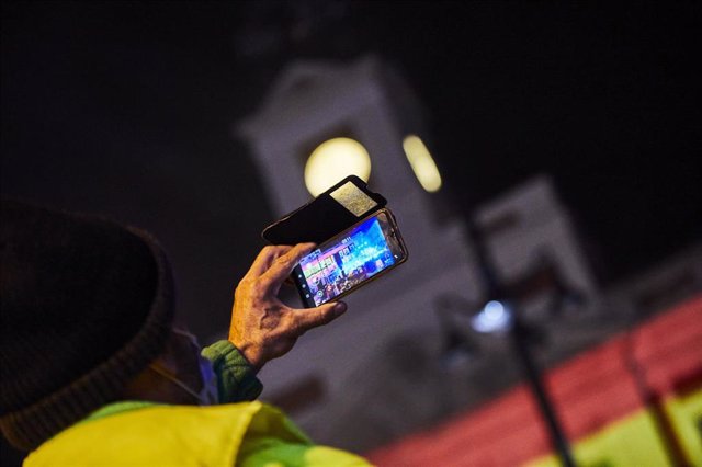 Archivo - Un hombre hace una foto al concierto de Nacho Cano minutos antes de las campanadas de Fin de Año, en la Puerta del Sol 