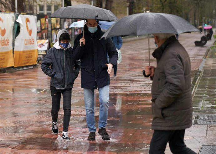 Archivo - Varias personas se refugian con un paraguas de la lluvia.