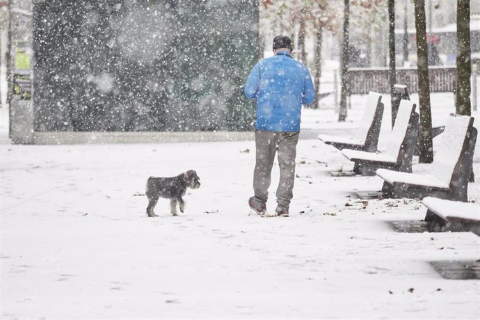 Un hombre camina sobre la nieve junto a su perro, a 28 de noviembre de 2021, en Pamplona, Navarra (España). Un total de 31 provincias se encuentran bajo diferentes niveles de riesgo por nieve, lluvia, viento, fuerte oleaje, deshielo y temperaturas mínim