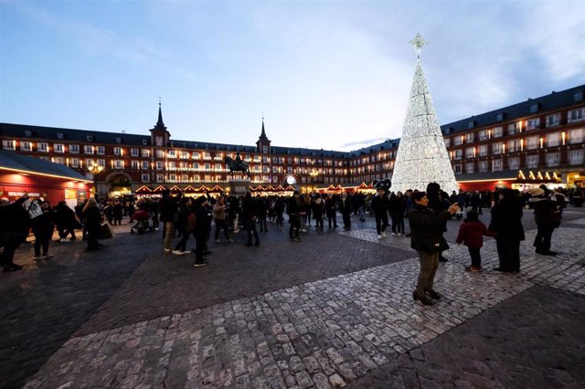 Archivo - Turistas y vecinos de Madrid visitan los puestos del mercadillo navideño de la Plaza Mayor de Madrid.