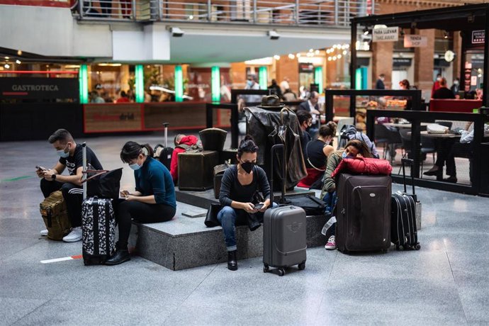 Archivo - Varias personas esperan la llegada de sus trenes en la estación de Madrid - Puerta de Atocha