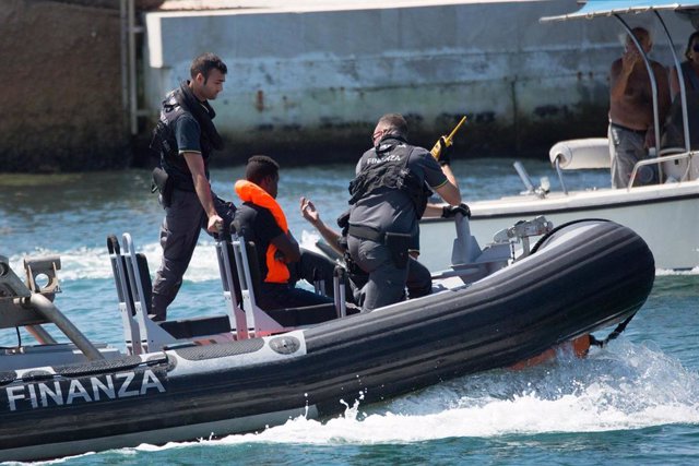 Archivo - Las fuerzas y cuerpos de seguridad italianos transportan a un migrante en el puerto de Lampedusa.