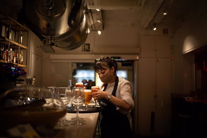 Archivo - Una camarera sirve una cerveza en el interior de un bar 