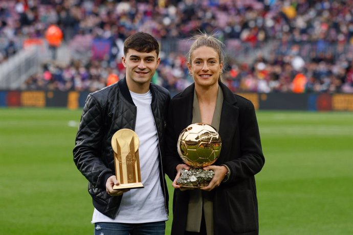 Pedri and Alexia Putellas of FC Barcelona poses for photo with golden boy and women ballon dor trophy during the La Liga match between FC Barcelona and Betis at Camp Nou Stadium on December 04, 2021 in Barcelona.
