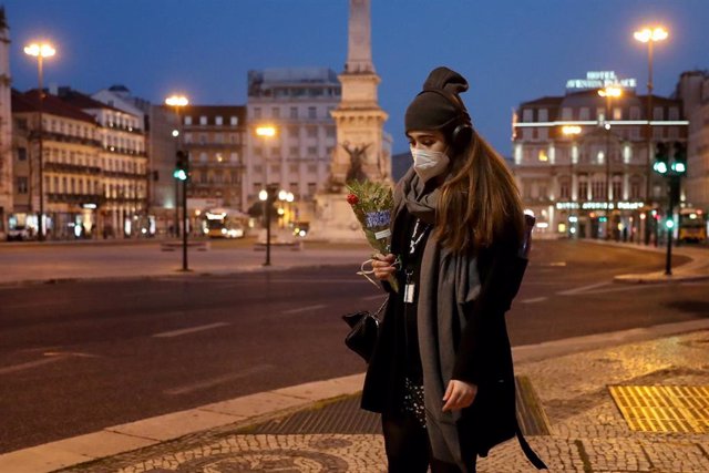 Archivo - Una mujer con mascarilla pasea por Lisboa