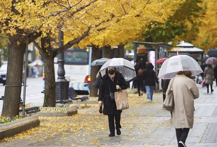 Archivo - Varias personas con paraguas pasean por una calle de Santander