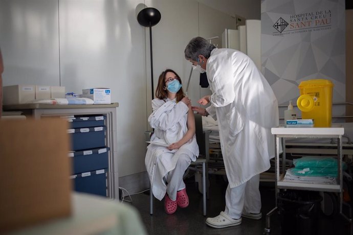 Archivo - Una enfermera vacuna a un profesional sanitario con la vacuna de Pfizer-BioNtech contra el COVID-19 en el Hospital de la Santa Creu i Sant Pau de Barcelona.