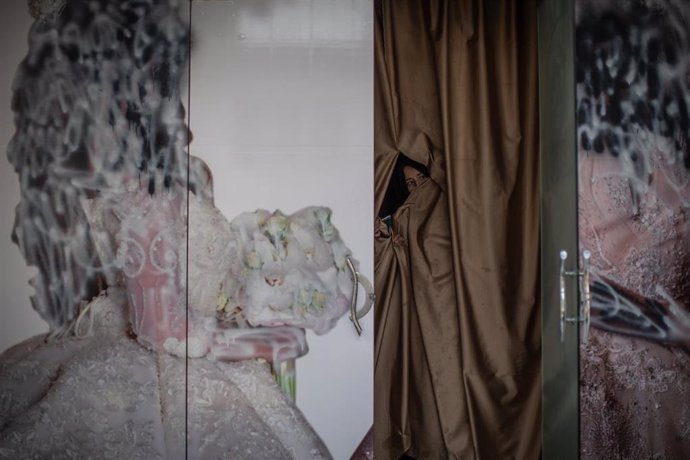Archivo - 22 September 2021, Afghanistan, Kabul: An Afghan woman peeks out a beauty parlour where the outside advertisement is defaced. Images depicting women have been removed or covered up since the Taliban took control of the country. Photo: Oliver W