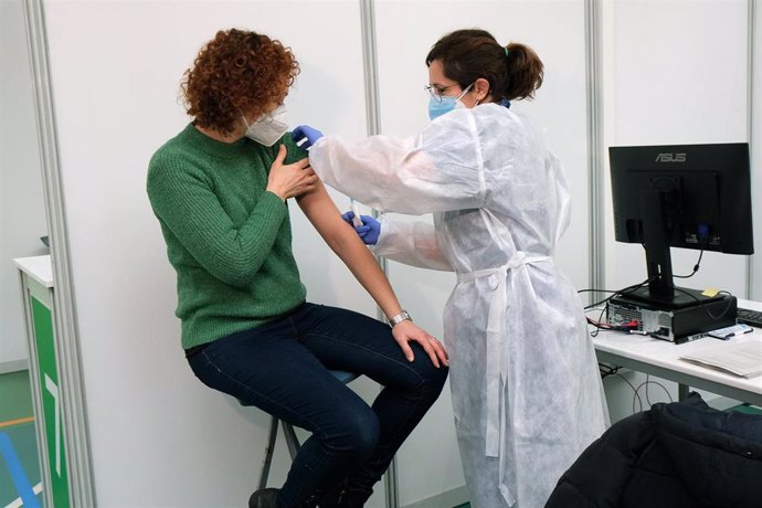 Archivo - Un empleada sanitaria suministra la vacuna contra la Covid-19 en el dispositivo de vacunación puesto en marcha en el polideportivo Germans Escalas.