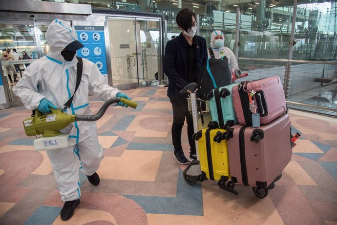 Archivo - 01 November 2021, Thailand, Samut Prakan: An airport worker disinfects a foreign traveler's luggage after his arrival on the first day of the country's reopening to foreign travelers at Suvarnabhumi International Airport. Thailand reopens the 