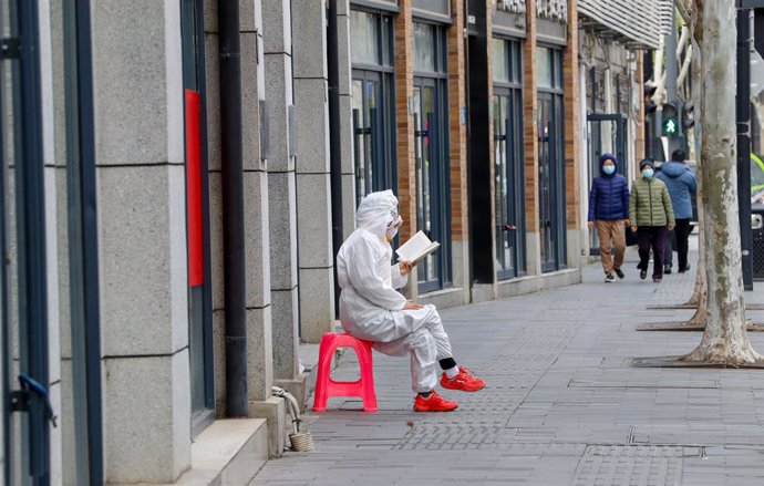 Archivo - Una perosna lee en una calle de Wuhan durante la pandemia.