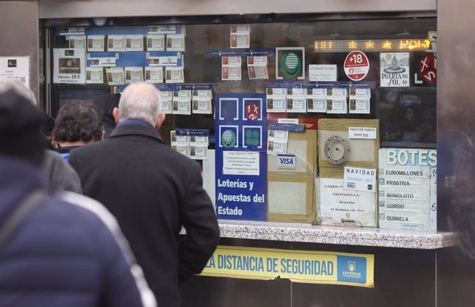 Varias personas en una administración de lotería de Navidad de la Puerta del Sol cuando quedan menos de tres semanas para el Sorteo Extraordinario de la Lotería de Navidad, a 7 de diciembre de 2021, en Madrid (España). 