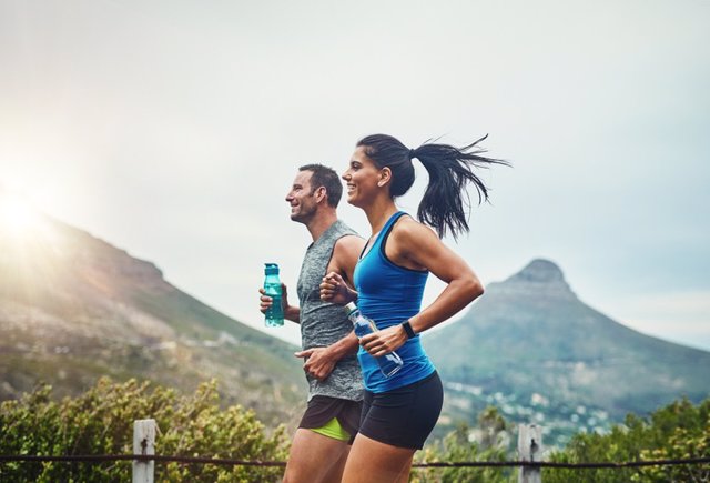 Pareja corriendo con una bebida isotónica. Electrolitos.