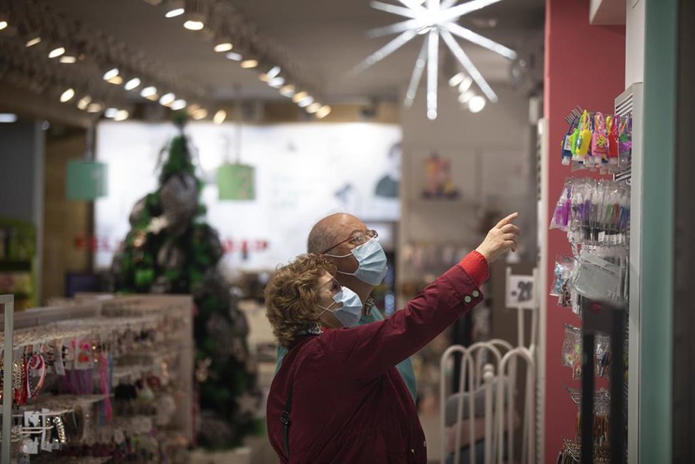 Archivo - Dos personas compran en una tienda ya decorada con motivos navideños. 