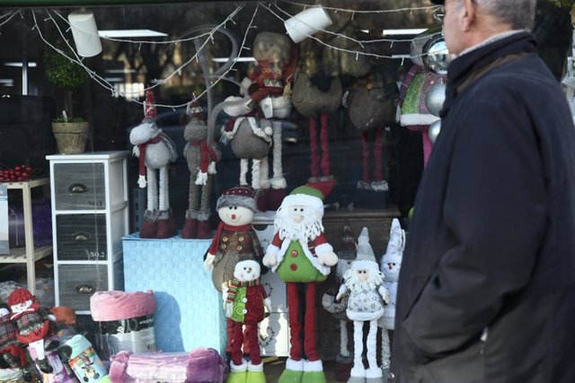 Archivo - Un anciano se para en el escaparate de una tienda que expone motivos navideños. 