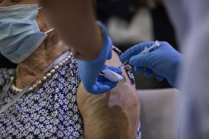 Archivo - Una sanitaria vacuna a una mujer con la tercera dosis del Covid-19