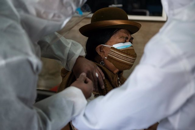 Archivo - 27 April 2021, Bolivia, La Paz: A woman with double oral-nasal protection Receives the Sputnik V Coronavirus vaccine in the library room of the Universidad de San Andres. Photo: Radoslaw Czajkowski/dpa