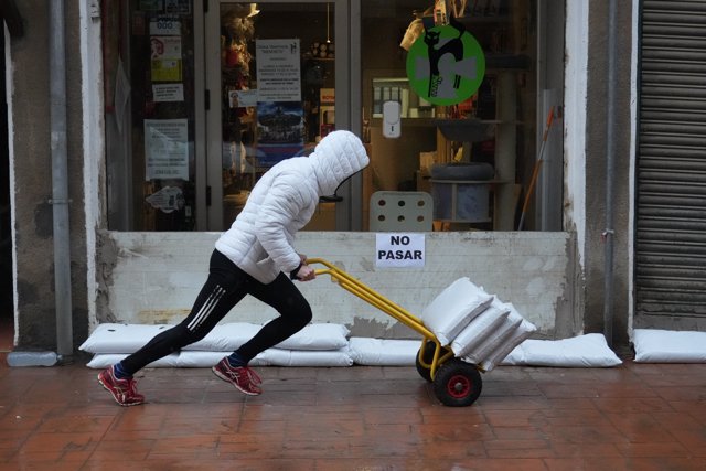 Un hombre desplaza sacos para tapar la entrada de un establecimiento y evitar la entrada de agua, en Güeñes (Bizkaia)