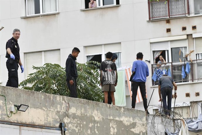 Archivo - Un policía nacional trabaja para que un grupo de menores migrantes abandone el tejado de una nave industrial