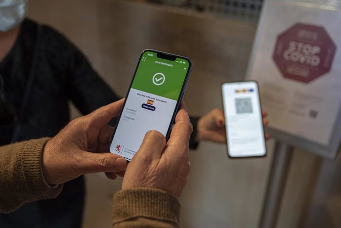 Una persona muestra su pasaporte Covid