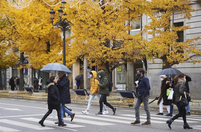 Archivo - Varias personas con paraguas cruzan un paso para peatones en Santander.- Archivo