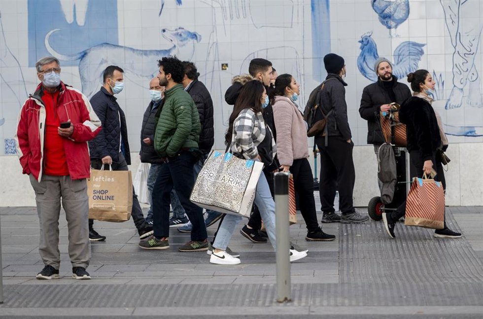 Varias personas caminan con bolsas con compras