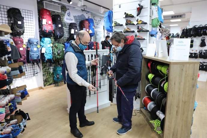 Archivo - Un trabajador de una tienda atiende a un cliente, en una foto de archivo.