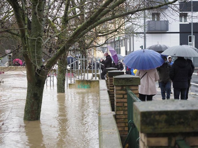 Varias personas caminan por una vía del barrio Rotxapea inundada, a 10 de diciembre de 2021, en Pamplona, Navarra, (España). El Gobierno de Navarra ha activado el nivel de preemergencia por inundaciones con el fin de mantener una vigilancia permanente y
