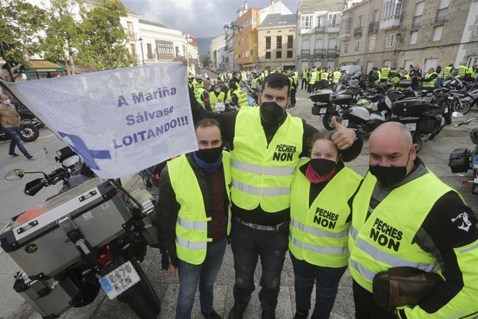 Cuatro personas posan junto a una pancarta donde se lee "A Mariña se salva luchando", antes del inicio de una caravana motera por el futuro de la planta de Alcoa en San Cibrao, a 21 de noviembre de 2021, en Ferreira de Valadouro, Lugo, Galicia (España).