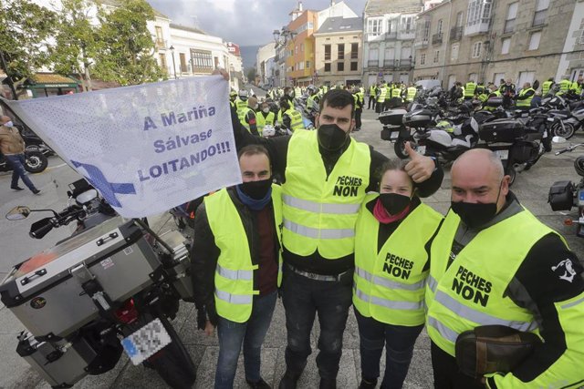 Cuatro personas posan junto a una pancarta donde se lee "A Mariña se salva luchando", antes del inicio de una caravana motera por el futuro de la planta de Alcoa en San Cibrao, a 21 de noviembre de 2021, en Ferreira de Valadouro, Lugo, Galicia (España). T