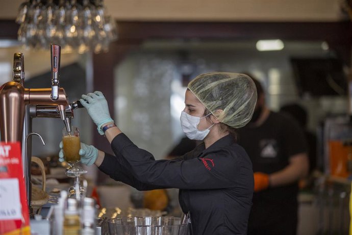 Archivo - Una empleada de un bar sirve una cerveza en el interior del establecimiento, en foto de archivo.