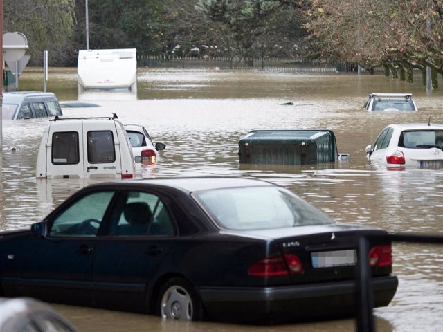 Varios vehículos en una vía inundada debido a la crecida del Arga en Pamplona