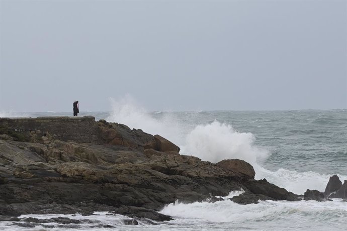 Una persona observa les ones que trenquen a la zona de les Esclaves, a 8 de desembre de 2021, a la Corunya, Galícia, (Espanya). La borrasca Barra ha fet que la Xunta hagi activat per a tot el litoral gallec una alerta taronja per temporal costaner. Sego