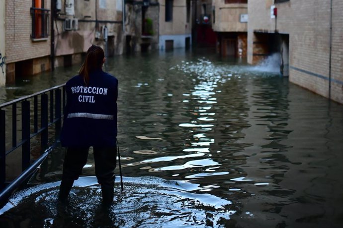 Una trabajadora de Protección Civil en una calle inundada por la crecida del Ebro en Navarra, a 12 de diciembre de 2021, en Tudela, Navarra (España). La Agencia Estatal de Meteorología (AEMET) espera que el tiempo se estabilice este domingo, cuando irán